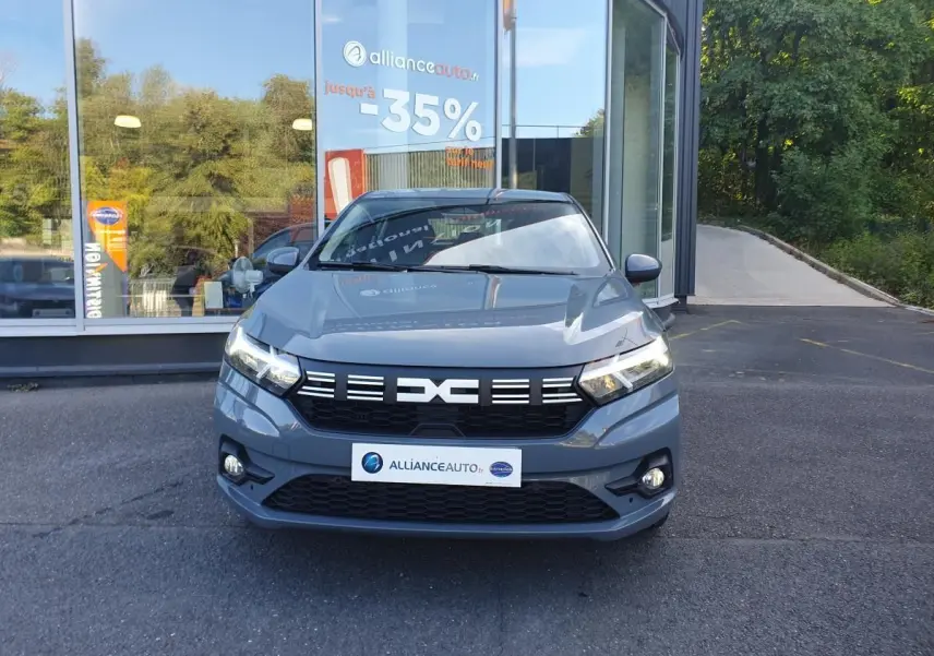 Vue avant d'une Dacia Sandero gris urbain 2024 avec signature lumineuse LED et calandre noire distinctive.