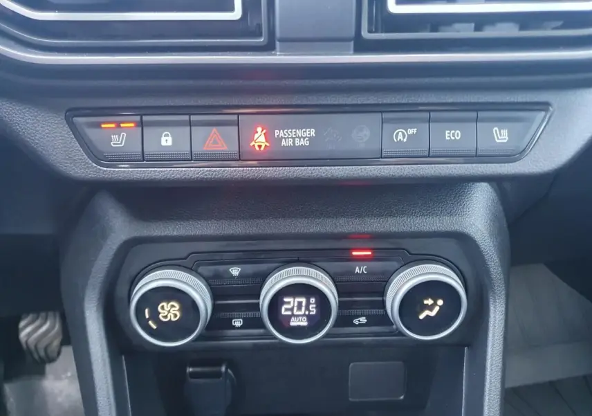 Tableau de bord de Dacia Sandero 2024, vue rapprochée des commandes de climatisation automatique et des boutons de sécurité.