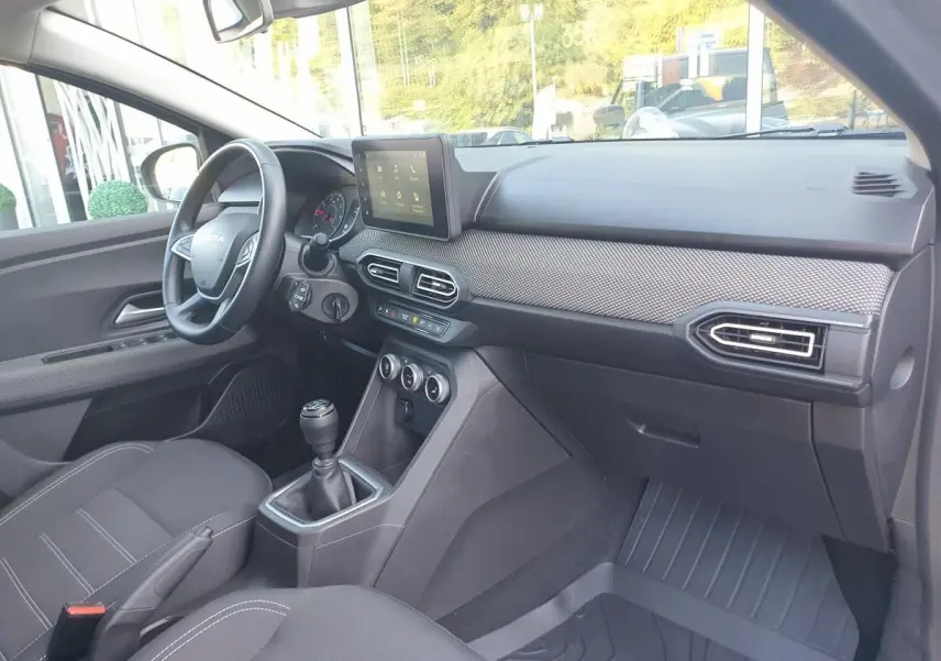 Intérieur de la Dacia Sandero 2024 vu côté conducteur, tableau de bord moderne avec écran tactile et finition grise.