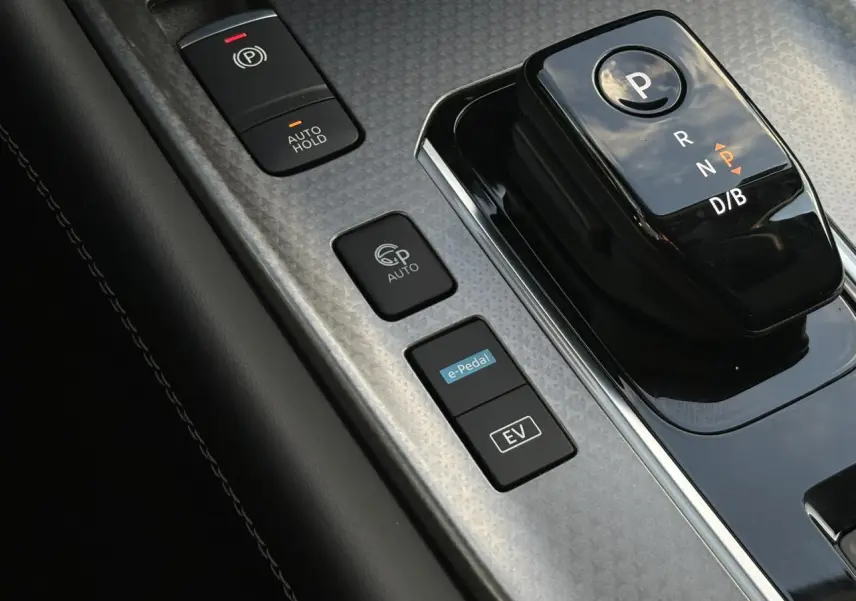 Gros plan sur la console centrale noire et grise du Nissan Qashqai III avec sélecteur de boîte auto et boutons e-Pedal et EV.