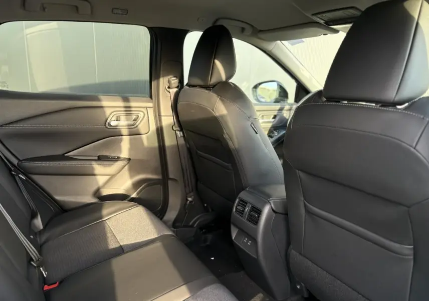 Vue intérieure arrière du Nissan Qashqai 2026 noir Kuro, sièges en cuir et tissu avec aérateurs centraux et ports USB.