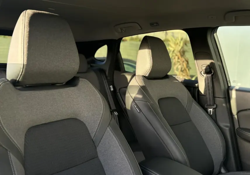 Vue intérieure sur les sièges avant gris et noirs du Nissan Qashqai III e-Power avec accoudoir central et ceinture côté droit.