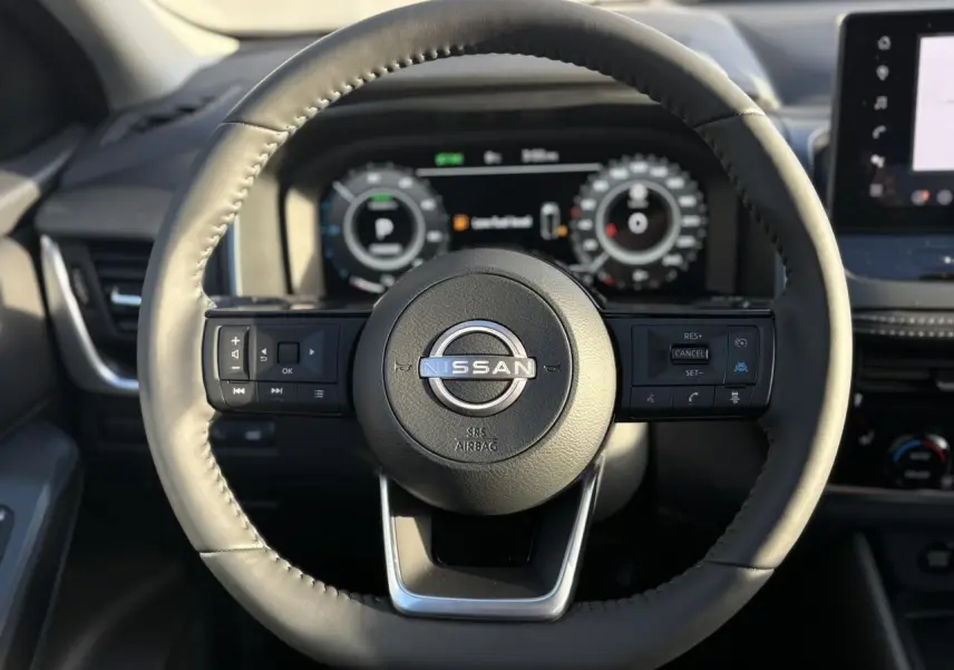 Vue rapprochée du volant noir en cuir du Nissan Qashqai 2026 avec commandes intégrées et tableau de bord numérique.