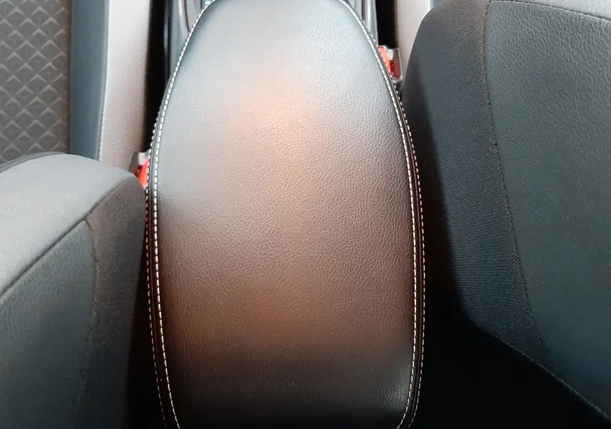 Vue rapprochée de l'accoudoir central en cuir gris avec surpiqûres blanches du Nissan Juke 2024 hybride.