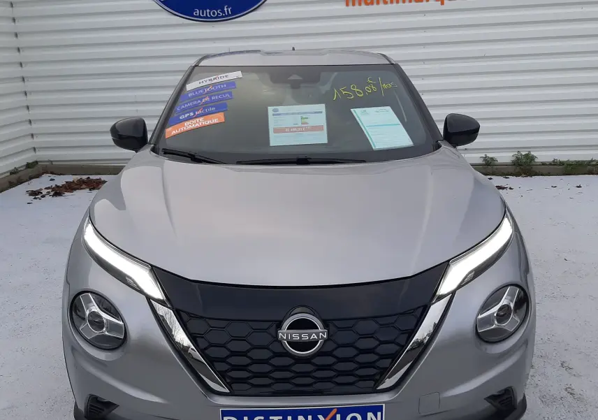 Vue frontale d'un Nissan Juke 2024 gris perle métal avec calandre noire et phares LED allumés.