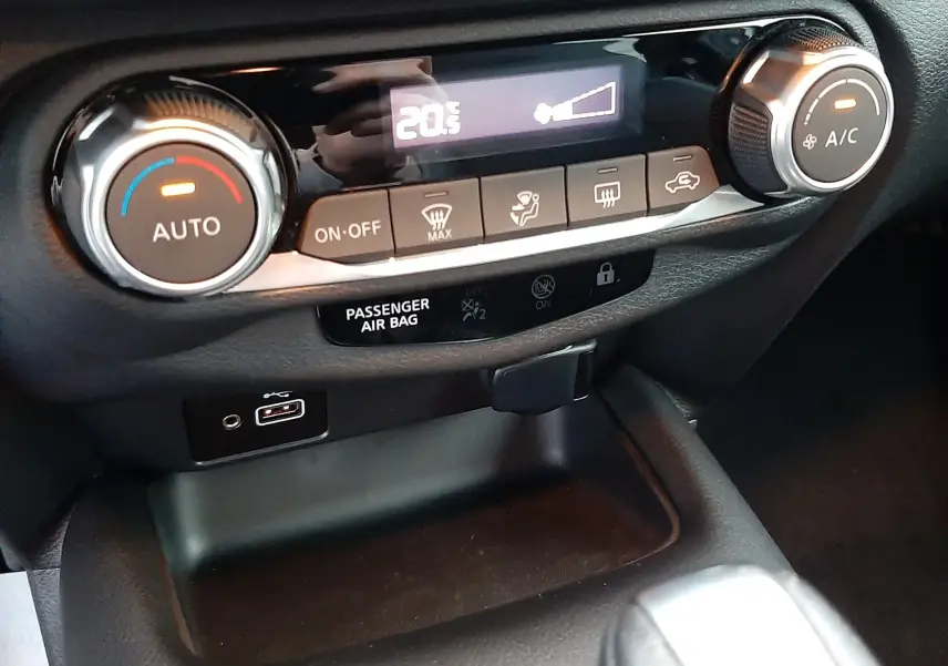 Gros plan sur la console centrale du Nissan Juke 2024, avec commandes climatisation et port USB visibles.