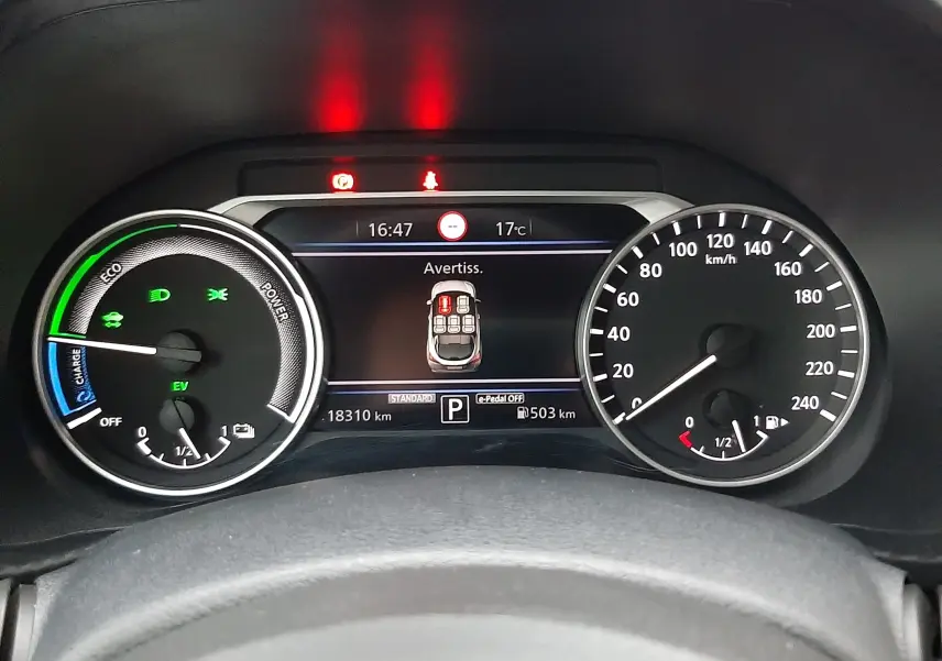 Vue rapprochée du tableau de bord numérique du Nissan Juke 2024, affichant les compteurs et alertes en cours.