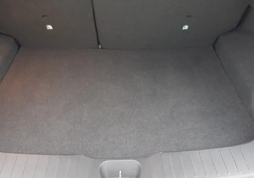 Coffre spacieux et vide du Nissan Juke 2024 gris perle métal, vue intérieure depuis l'arrière du véhicule.