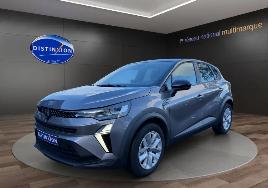 Renault Captur 2024 gris Cassiopée toit noir, vue 3/4 avant droit avec feux diurnes allumés et caméra de recul visible.