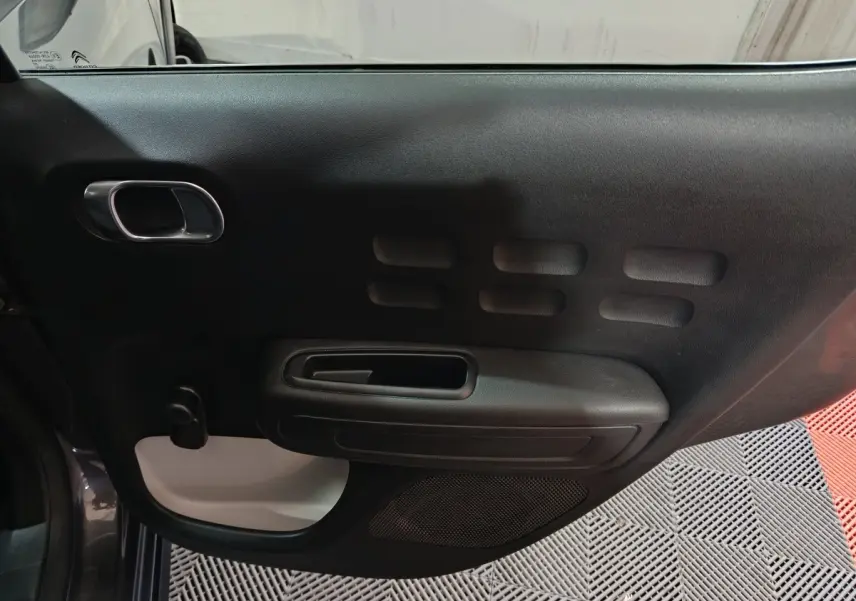 Vue intérieure de la porte avant gauche noire de la Citroën C3 2024 avec poignée chromée et panneau texturé.