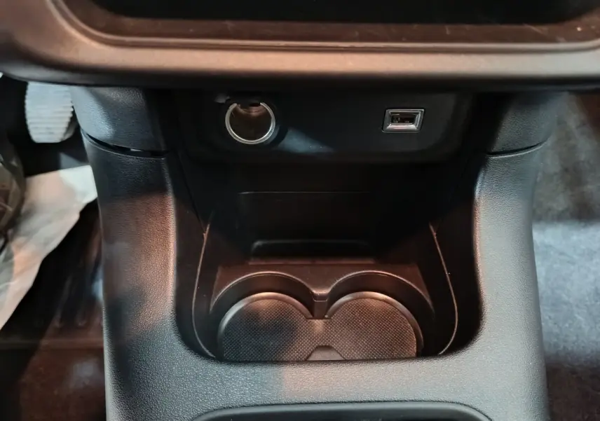 Gros plan sur la console centrale noire de la Citroën C3 2024 avec prise 12V et port USB visible.