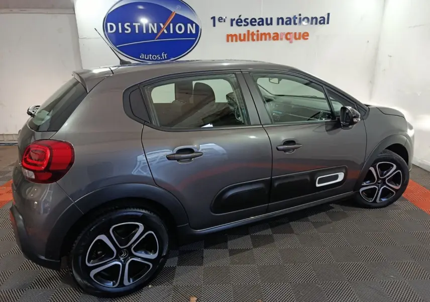 Vue latérale droite d'une Citroën C3 BlueHDi 100 gris foncé avec protections latérales noires et jantes stylisées.