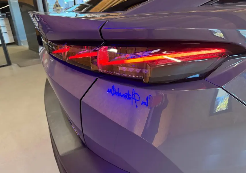 Gros plan sur le feu arrière droit rouge d'une Peugeot 408 gris métallisé, avec reflets intérieurs et lignes anguleuses.