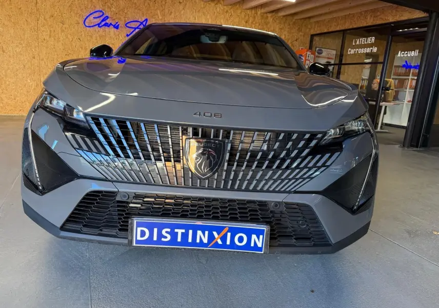 Vue de face d'une Peugeot 408 gris métallisé avec calandre verticale distinctive et logo lion noir brillant.