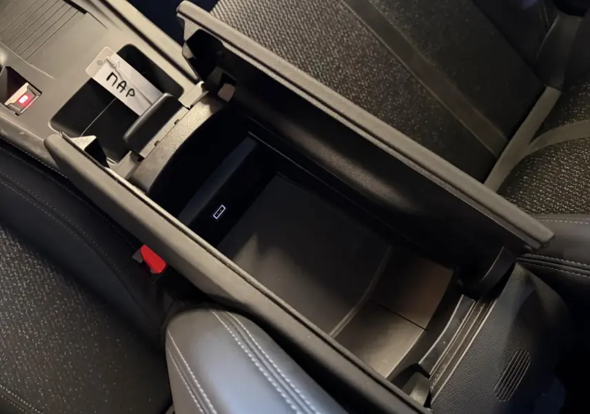 Vue rapprochée de la console centrale ouverte avec rangement intérieur et surpiqûres Vert Adamite dans une Peugeot 408 gris Selenium.