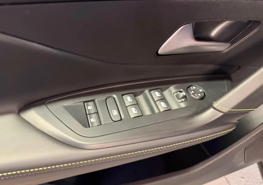 Détail des commandes de lève-vitres et rétroviseurs sur la porte avant gauche du Peugeot 408 gris, avec surpiqûres vertes.