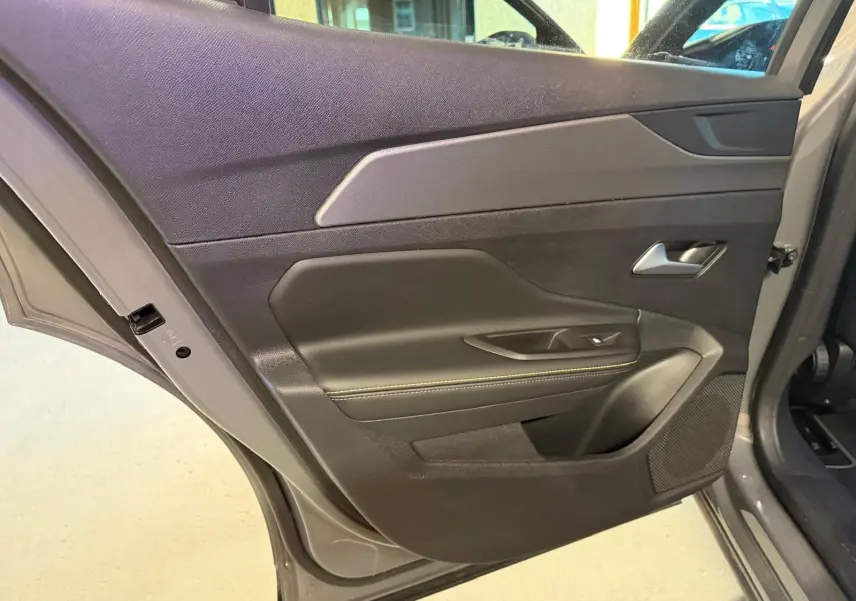 Vue rapprochée de la porte arrière gauche gris Selenium de la Peugeot 408 2025 avec surpiqûre verte et poignée alu.
