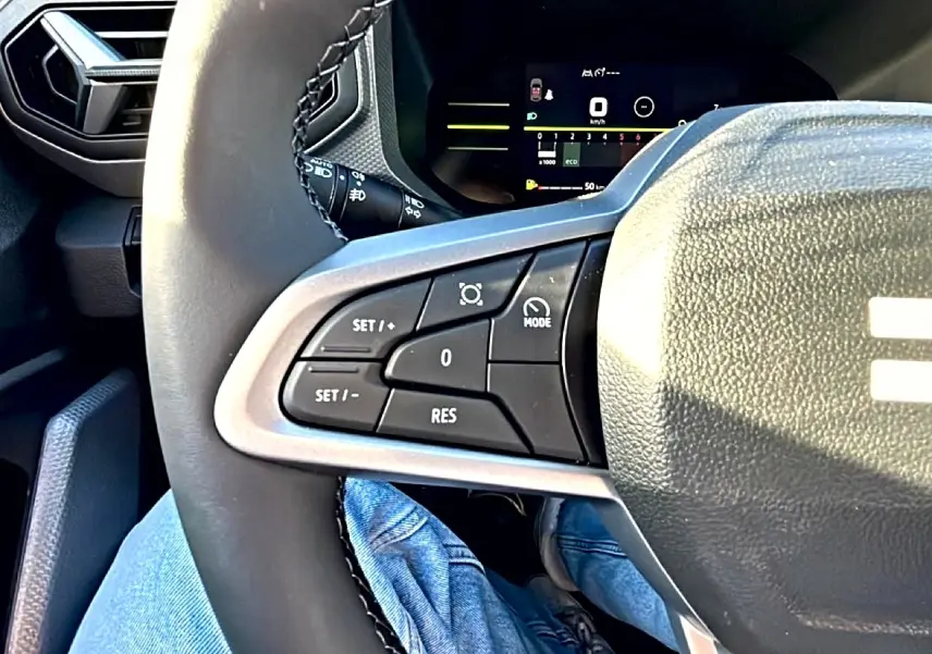 Gros plan sur le volant multifonction noir du Dacia Duster 2026, avec commandes de régulateur de vitesse visibles côté gauche.