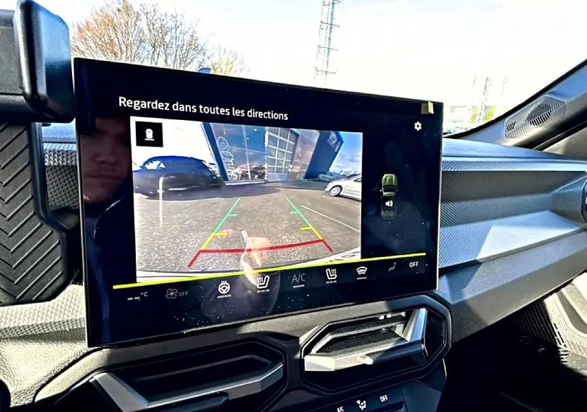 Écran tactile intérieur du Dacia Duster 2026 montrant la caméra de recul, avec tableau de bord et aérateurs noirs.