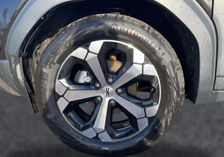 Gros plan sur la roue avant gauche du Dacia Duster noir 2026, jante alu à design géométrique bicolore.