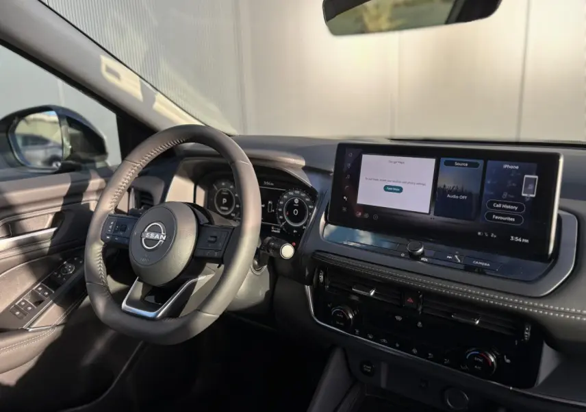 Vue intérieure côté conducteur du Nissan Qashqai III e-Power 2026, avec volant cuir et écran tactile 12,3 pouces allumé.