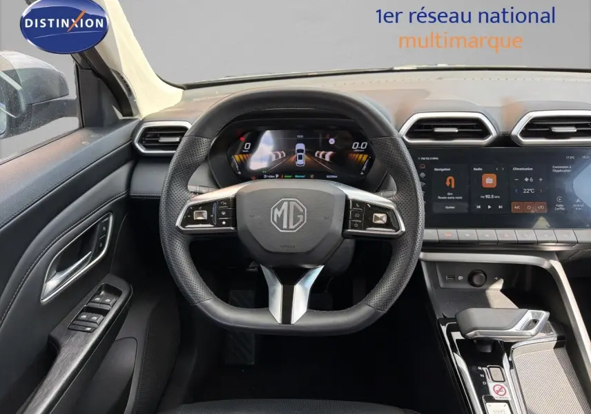 Vue intérieure centrée sur le volant MG d’un MG ZS 1.5L Hybrid+ gris Hampstead avec tableau de bord numérique et écran tactile.