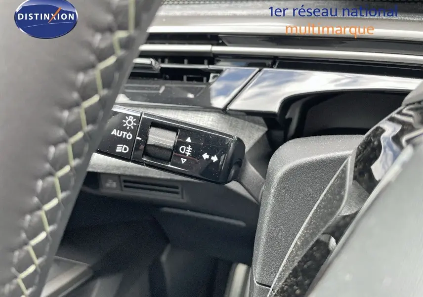 Gros plan sur la commande des feux à gauche du volant d’un Peugeot 5008 Hybrid blanc Okenite métal toit noir 2025.