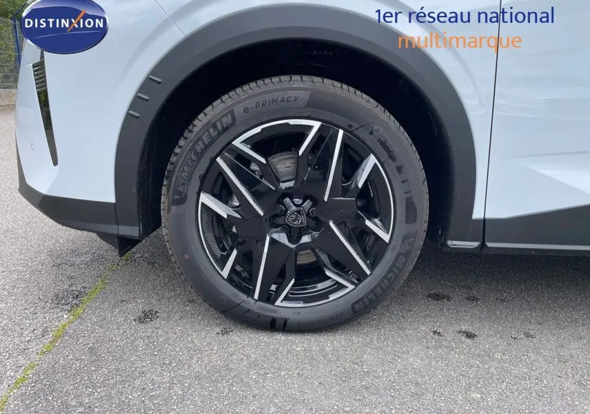 Gros plan sur la roue avant gauche du Peugeot 5008 blanc Okenite avec jante noire et détails argentés.