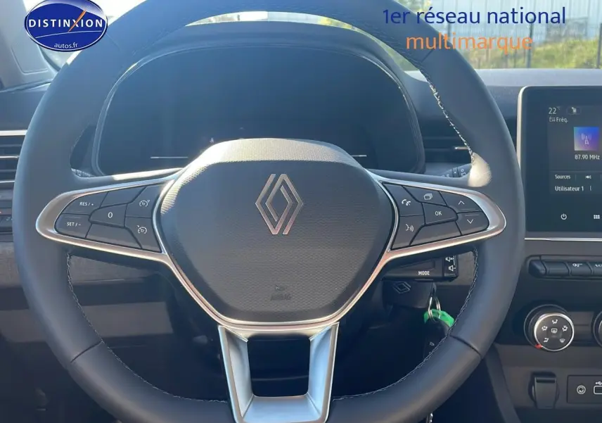 Volant multifonction Renault Clio V en gros plan avec tableau de bord et écran tactile visible en arrière-plan.