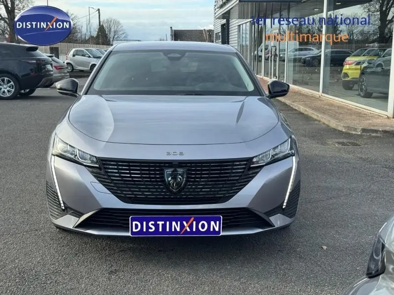 Vue avant frontale d'une Peugeot 308 2024 gris Artense avec calandre noire et feux LED verticaux distinctifs.