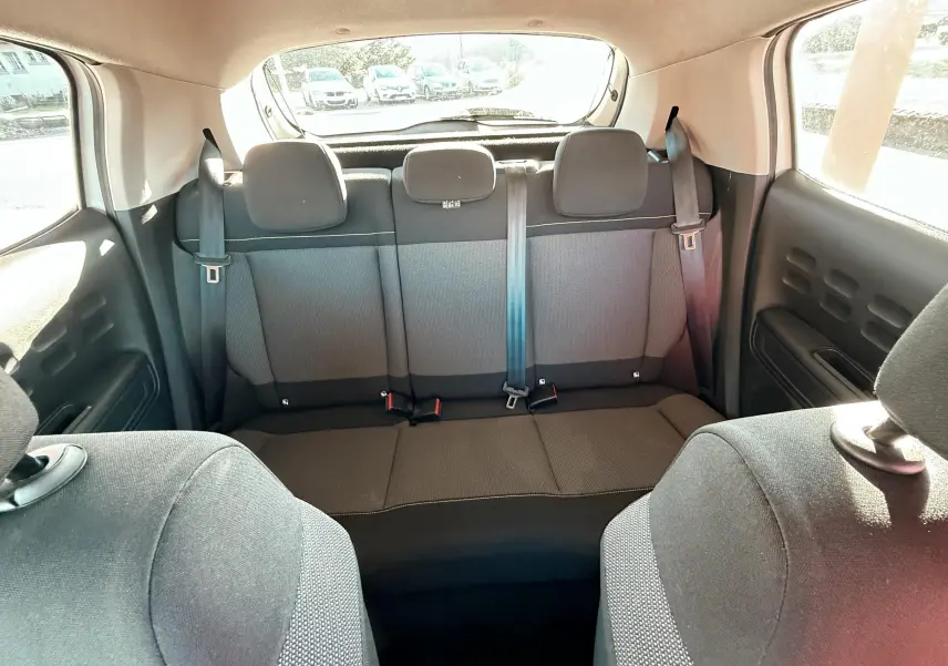 Vue intérieure arrière montrant la banquette arrière en tissu gris-noir de la Citroën C3 blanche de 2017.