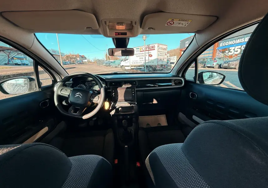 Vue intérieure avant de la Citroën C3 2017, tableau de bord et volant noir avec sièges tissu gris foncé.