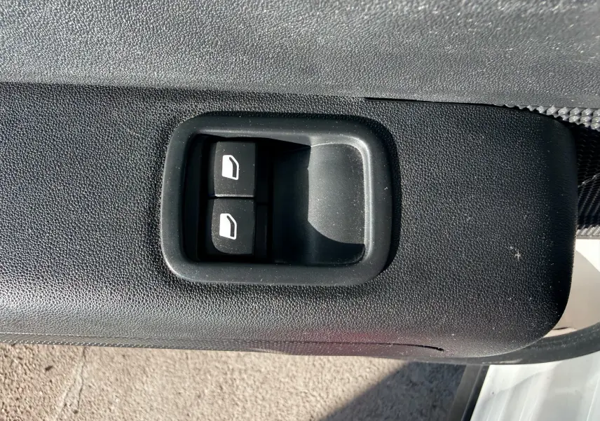 Gros plan sur les commandes de lève-vitres noirs intégrées à la porte côté gauche d'une Citroën C3 blanche.