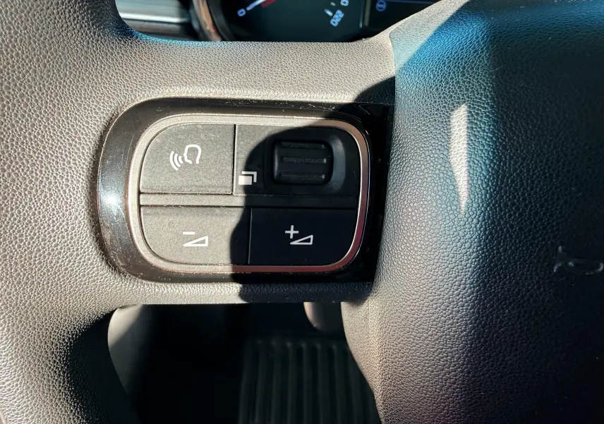 Gros plan sur les commandes de volume et téléphone au volant noir de la Citroën C3 2017.