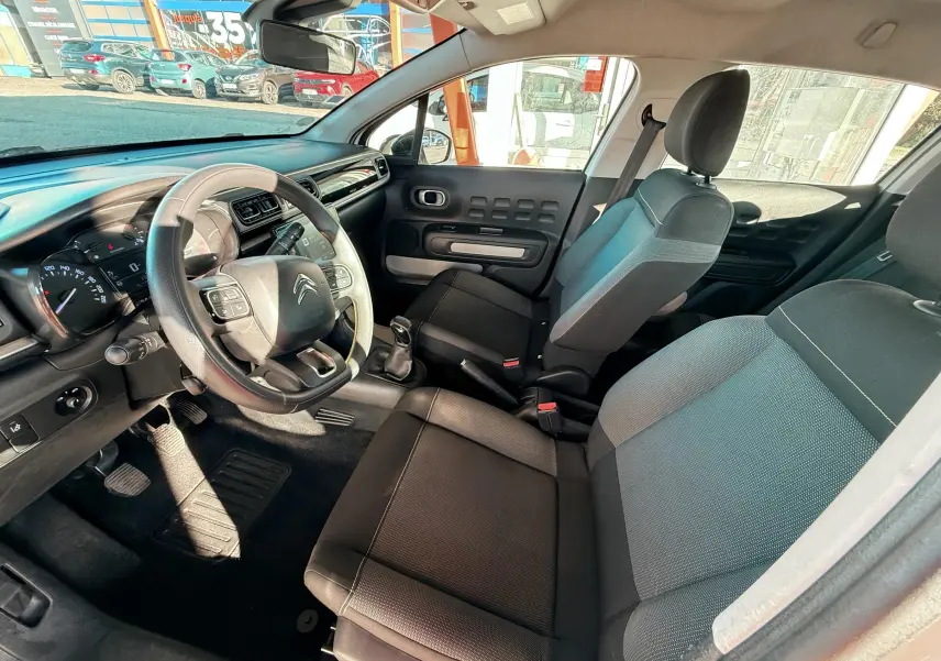 Vue intérieure côté conducteur de la Citroën C3 2017 avec sièges tissu gris noir et volant multifonction.