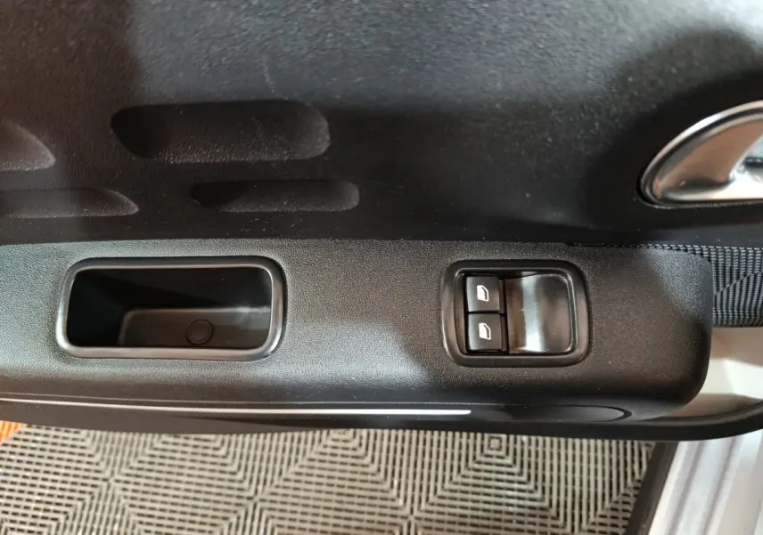 Vue rapprochée de la porte côté conducteur d'une Citroën C3 gris clair, avec commandes électriques des vitres.