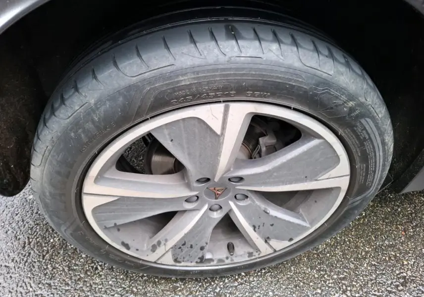 Gros plan sur la jante alu grise avec logo CUPRA au centre, sur le côté droit d'une CUPRA Formentor noire.