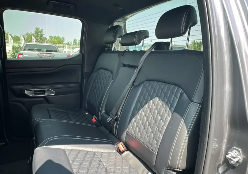 Vue intérieure côté droit des sièges arrière en cuir noir matelassé du Ford Ranger gris carbone 2026 avec rideau coulissant.