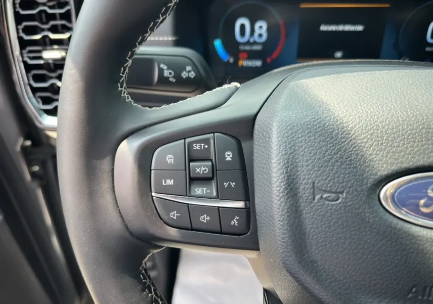 Gros plan sur le volant cuir multifonctions du Ford Ranger gris carbone, avec commandes de régulateur et assistance visibles.