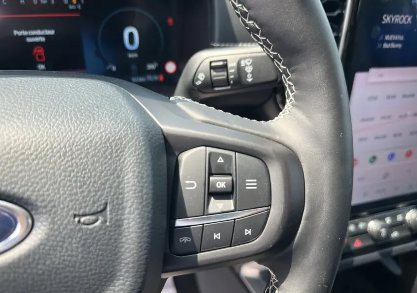 Gros plan sur le volant cuir multifonctions du Ford Ranger 2026, avec commandes intégrées et écran tactile en arrière-plan.