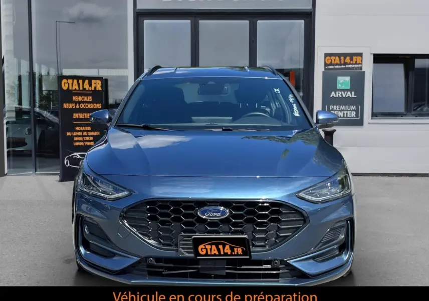 Vue frontale d'une Ford Focus SW 2025 bleu métallisé avec calandre hexagonale et logo Ford visible.