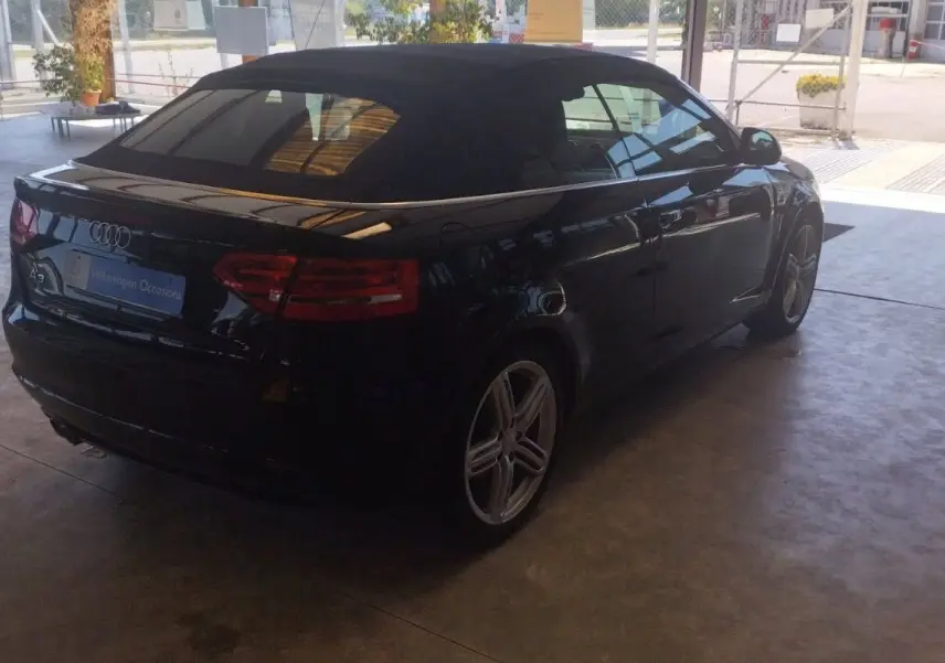 Audi A3 Cabriolet noir vue 3/4 arrière droit, capote fermée, jantes alliage et feux arrière allumés.