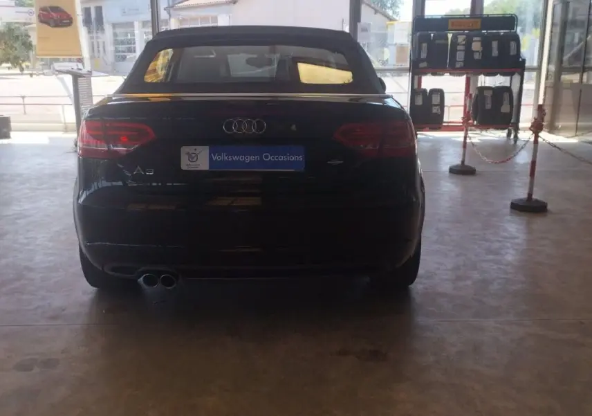 Vue arrière d'une Audi A3 Cabriolet noire de 2010 avec capote fermée, en intérieur de showroom.