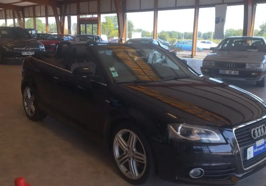Audi A3 Cabriolet noir 2010 vue 3/4 avant droit, capote ouverte, jantes alliage et intérieur noir visible.