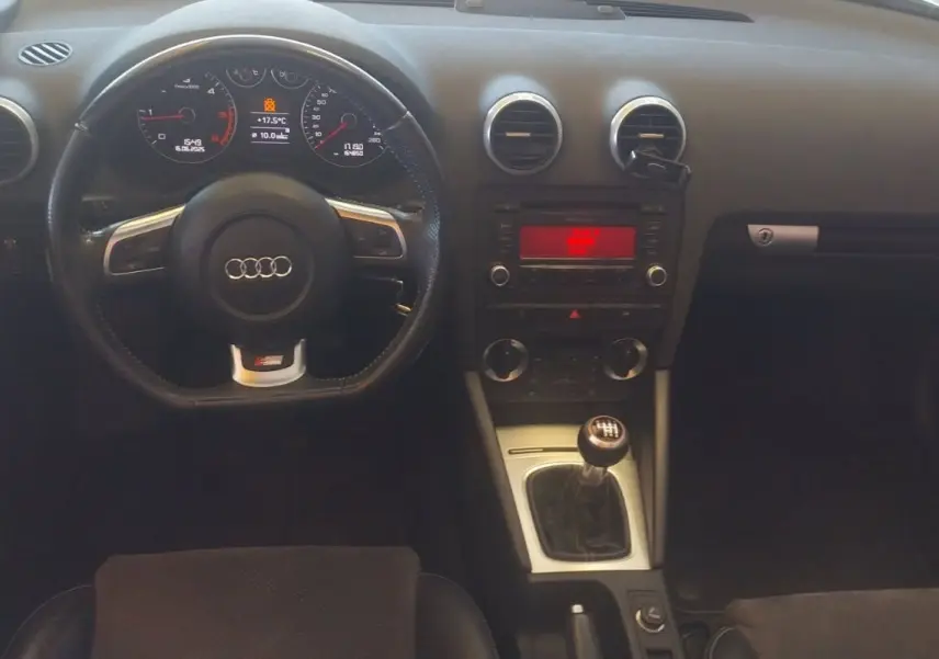 Vue intérieure de l'Audi A3 Cabriolet 2010 noir, tableau de bord et volant sport avec levier de vitesse manuel visible.