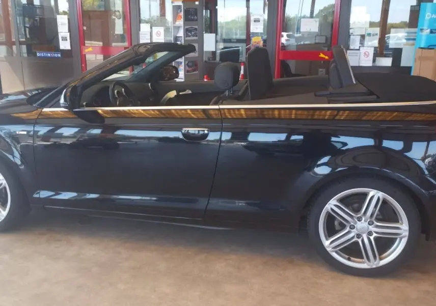 Audi A3 Cabriolet noir vue de profil côté gauche, capote ouverte et jantes alliage cinq branches visibles.