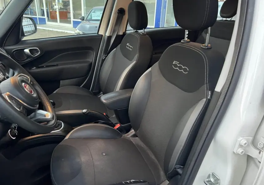 Vue intérieure côté conducteur de la Fiat 500L 2017 montrant les sièges noirs avec logo 500 brodé sur les appuie-têtes.