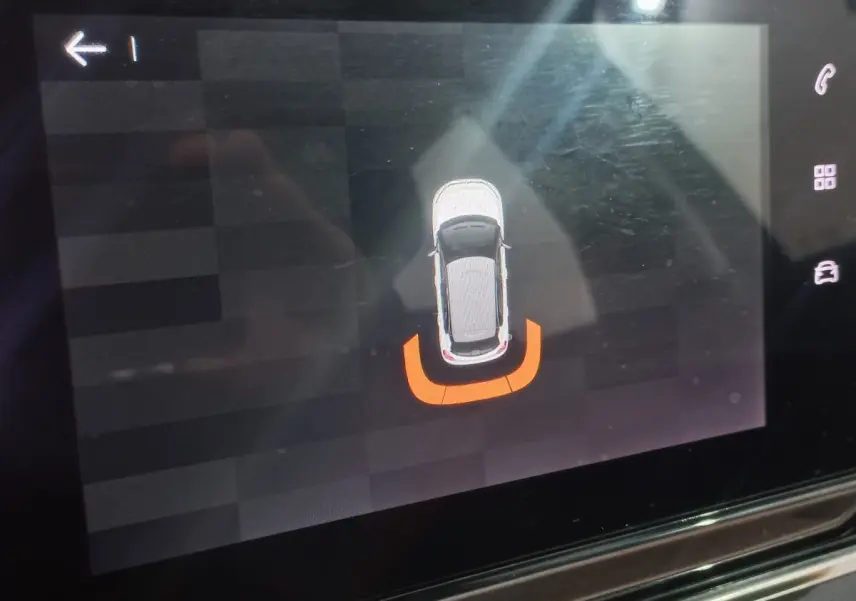 Affichage tactile montrant la vue aérienne d'une Citroën C3 noire avec alerte de proximité arrière en orange.