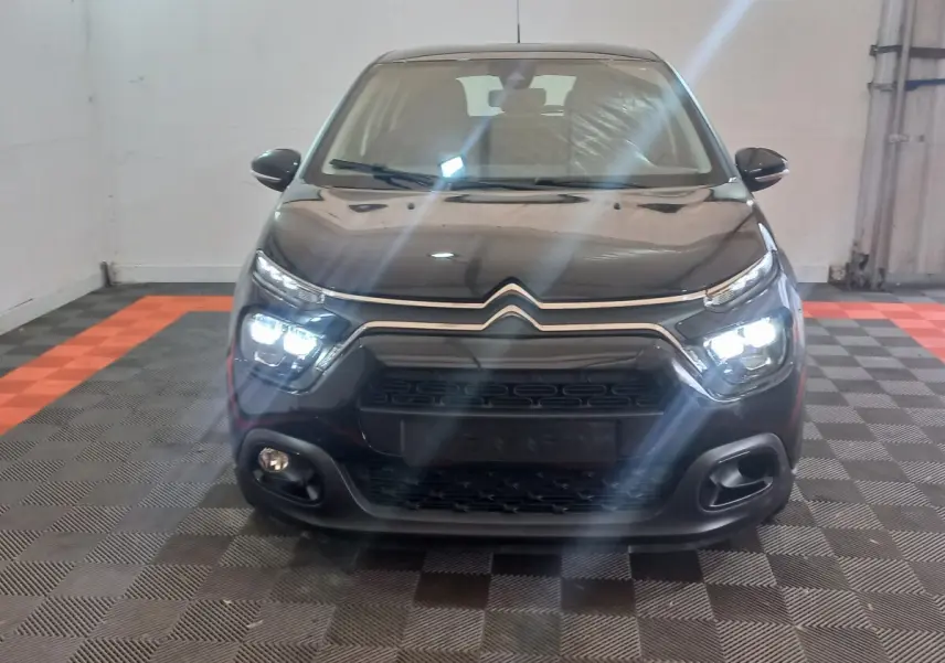 Vue frontale d'une Citroën C3 noire 2024 avec phares LED allumés dans un garage intérieur.