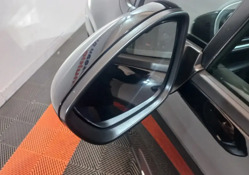 Rétroviseur extérieur droit noir brillant de la Citroën C3 2024, avec caméra intégrée et carrosserie noire visible en reflet.